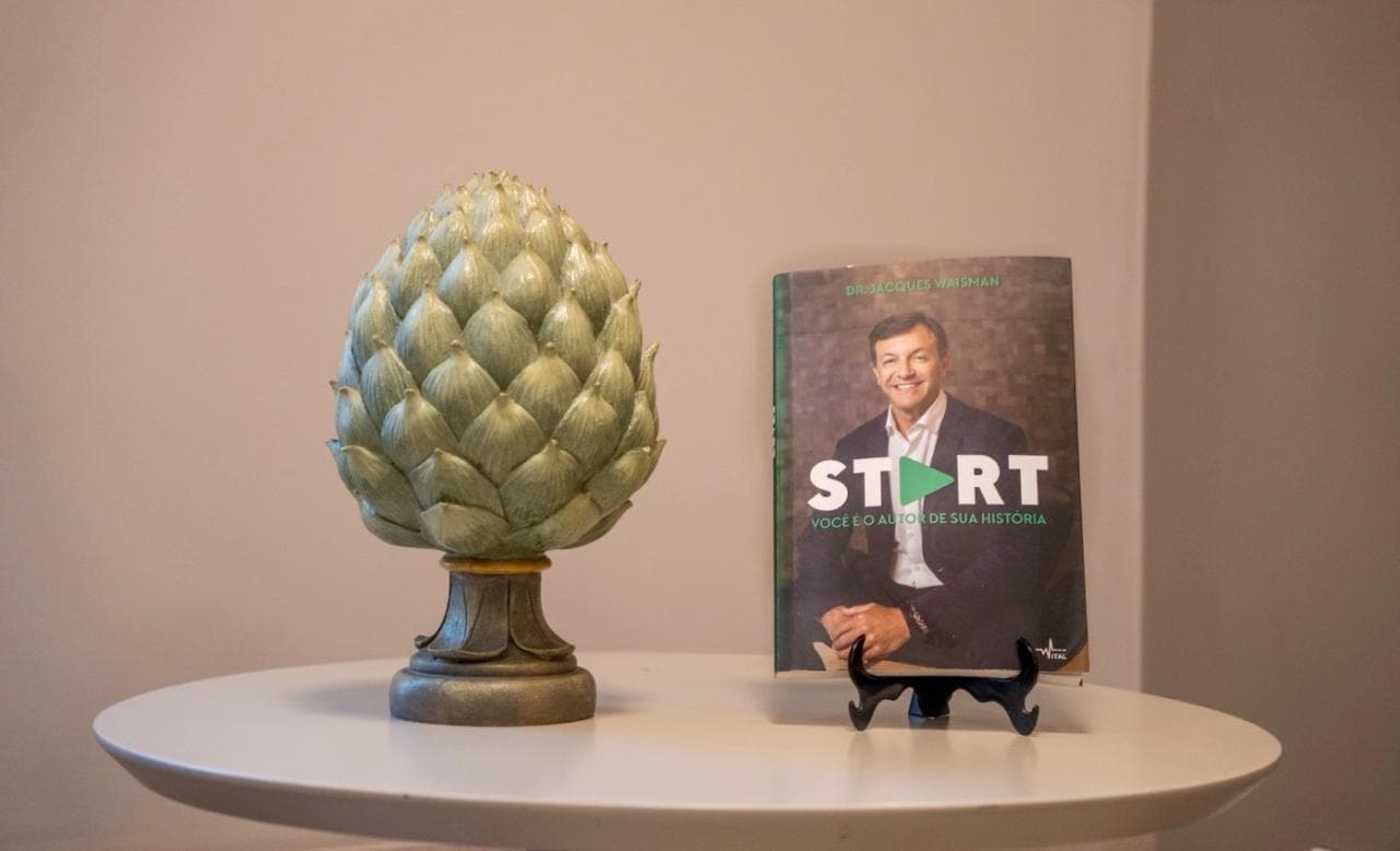 Livro START, do Dr. Jacques Waisman, sobre uma mesa ao lado de um objeto decorativo